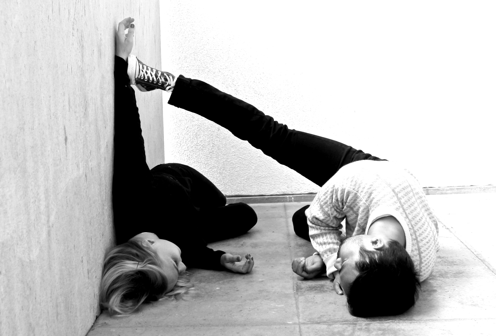 The performers of And Then They Were curl together in a concrete interior.